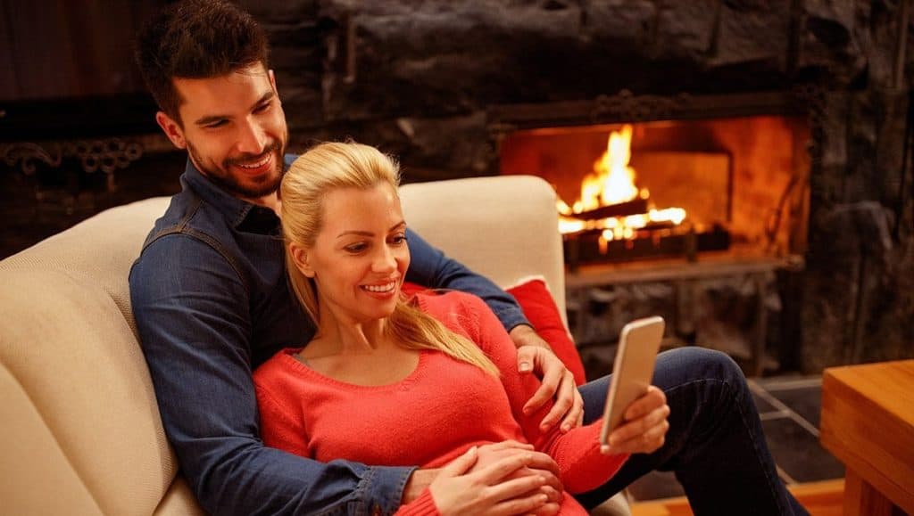 Couple on couch by wood fire image on safe home fireplace website